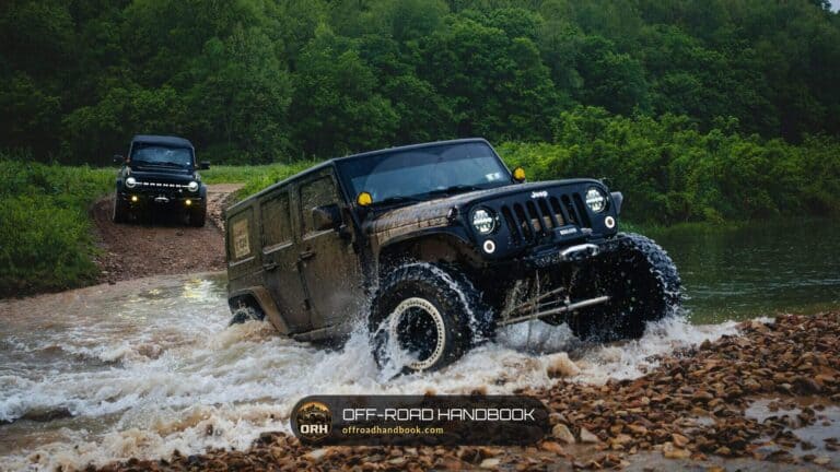 Black Jeep splashing through a shallow rocky river