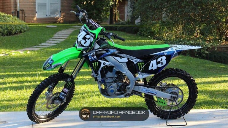 Green Kawasaki motocross bike with number 43 plates and Monster Energy graphics parked on a stand on a lawn
