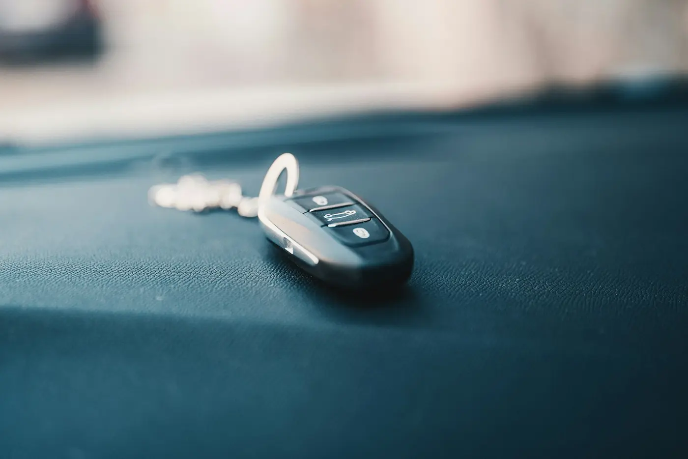 Black car key fob with three buttons lying on a dashboard