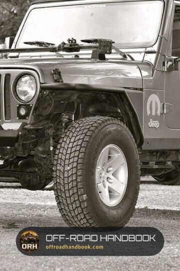 Lifted Jeep Wrangler TJ on oversized all-terrain tires with a stinger bumper, black and white photo