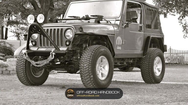 Lifted Jeep Wrangler TJ on oversized all-terrain tires with a stinger bumper, black and white photo