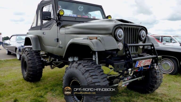 Heavily lifted olive-green Jeep CJ with oversized tires parked on grass