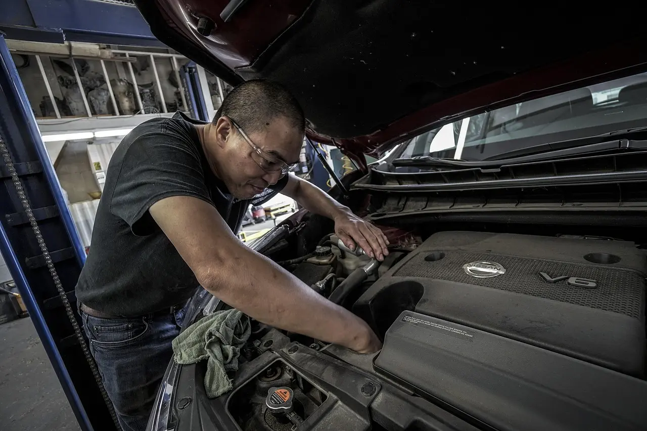 Mechanic leaning over an open hood to work on a V6 engine