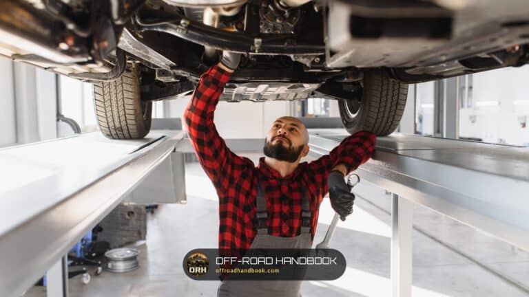 Mechanic in a plaid shirt working on the underside of an SUV raised on a service lift