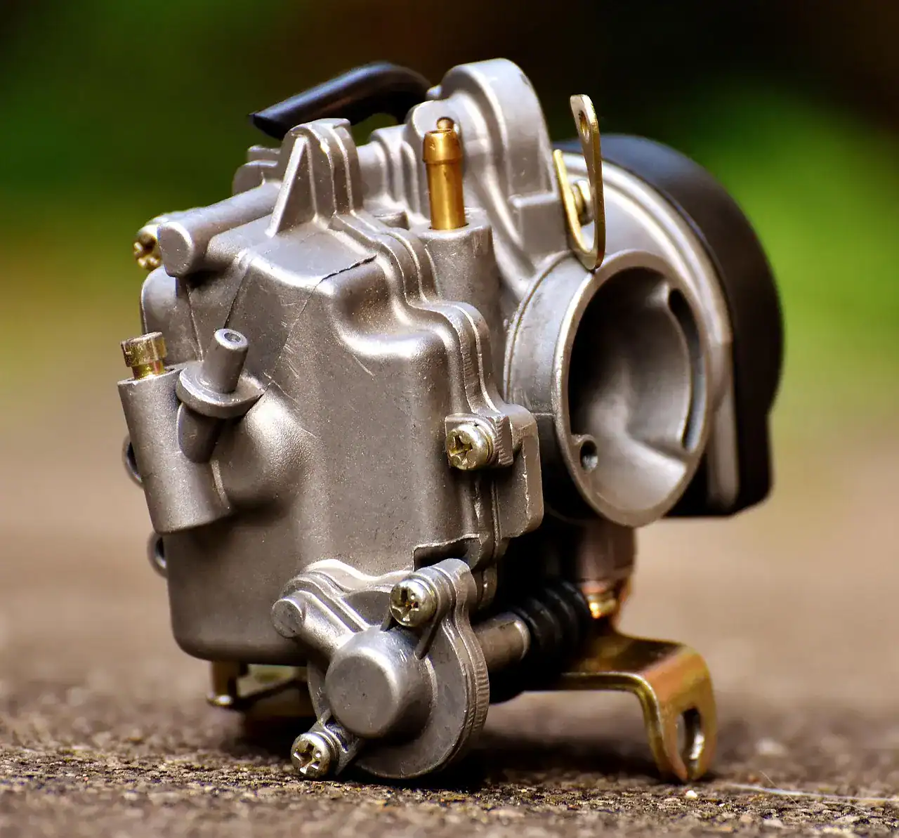 Close-up of a small-engine carburetor with its float bowl, jets and linkage