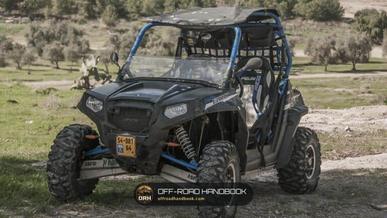 Black Polaris RZR 800 side-by-side parked on a dirt trail with a roll cage and mud tires, used as a generic UTV photo