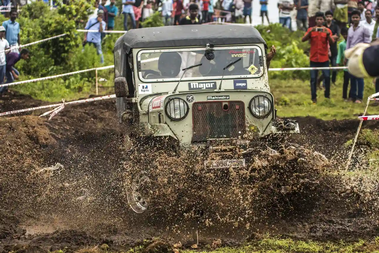 Open off-road jeep splashing through a mud pit at an off-road event