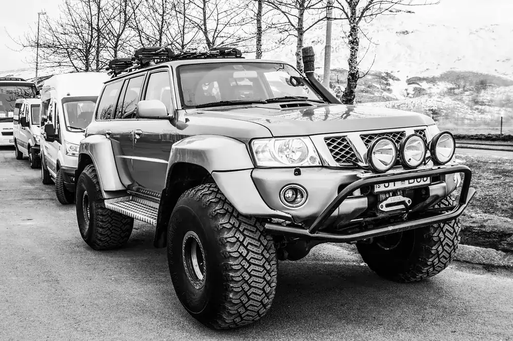 Lifted Nissan Patrol 4x4 on oversize all-terrain tires with a bull bar and roof rack