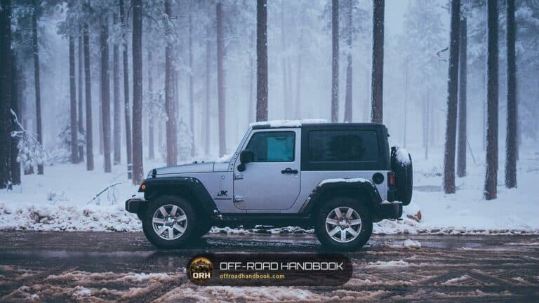 Silver Jeep Wrangler parked on a snowy road in a pine forest in winter