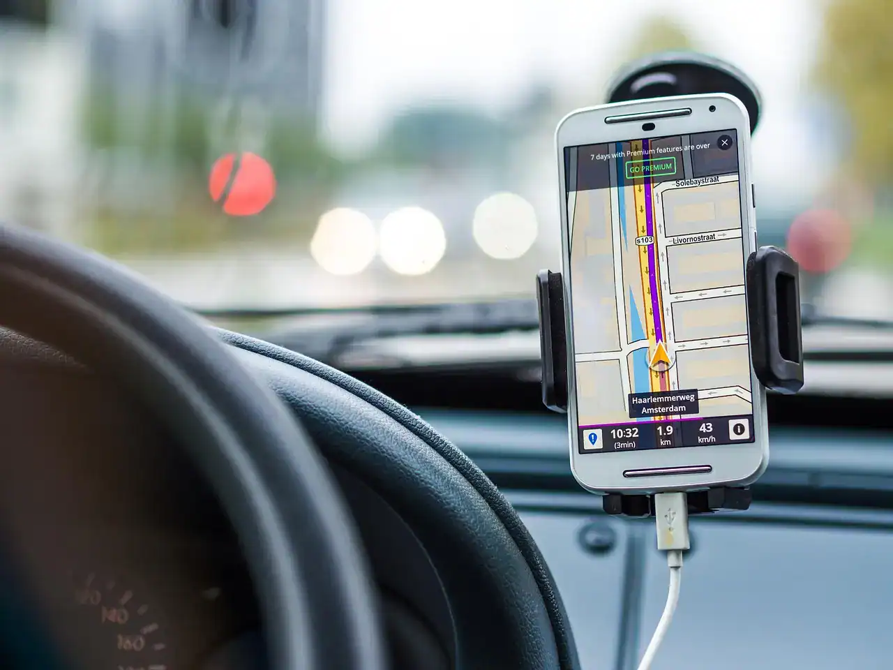 Smartphone showing a navigation map on a dashboard mount inside a vehicle