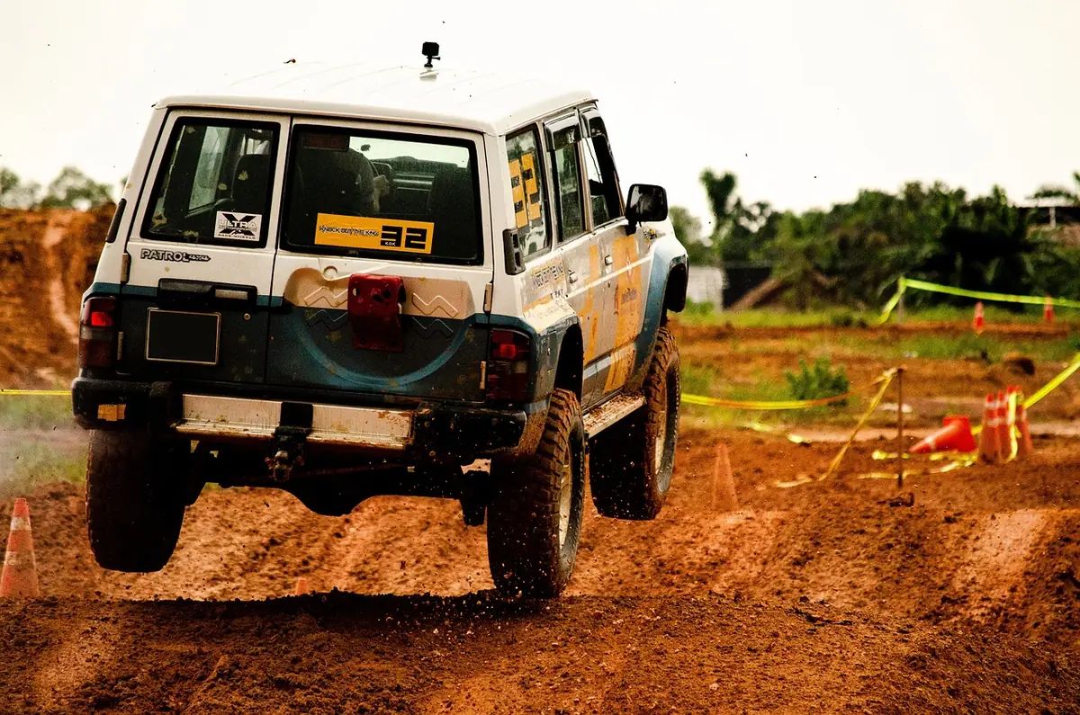 Nissan Patrol 4x4 with a rear wheel off the ground showing axle articulation on a dirt course