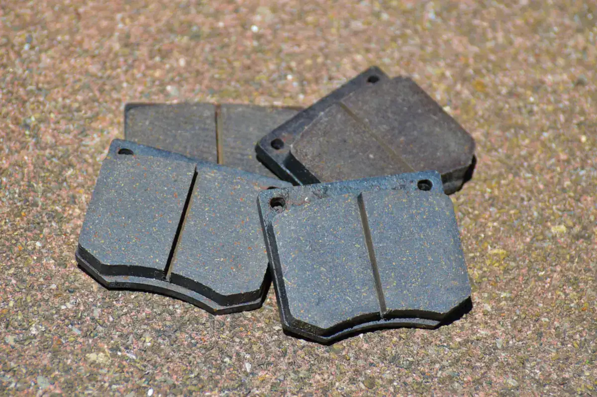 Set of disc brake pads lying on gravel, used to check lining wear (generic stock photo, not a Pioneer 1000)