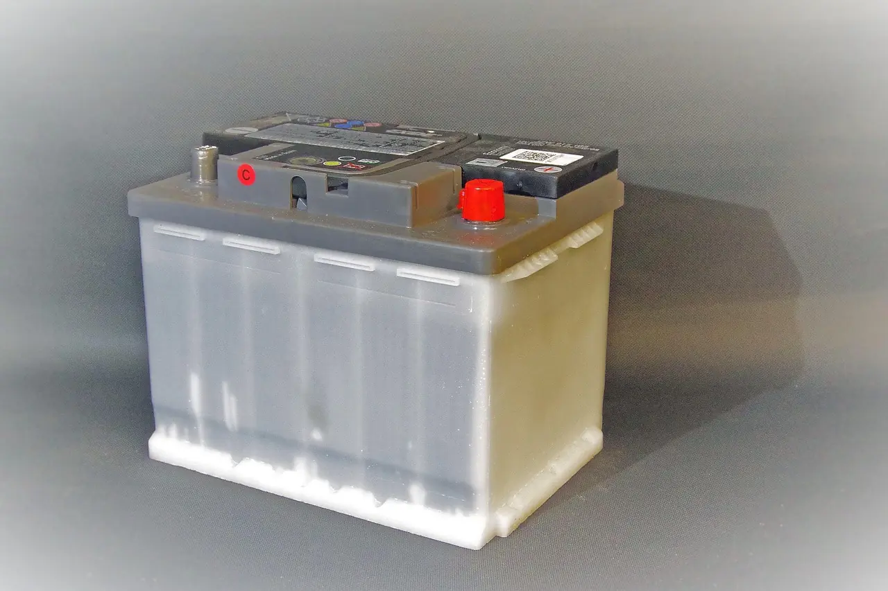 A lead-acid battery with red and gray terminal caps on a gray background