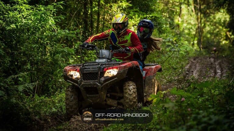 Two riders on a red utility ATV on a forest trail — Off-Road Handbook
