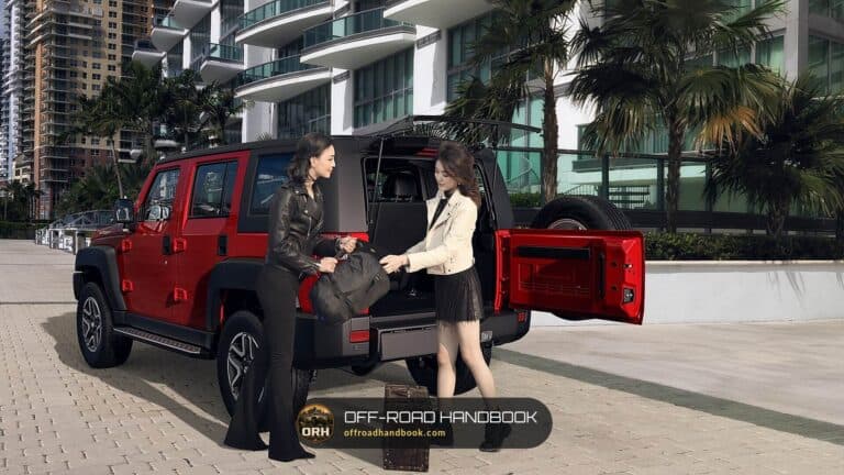 Red SUV with its rear door open while two people load a bag into the cargo area — Off-Road Handbook