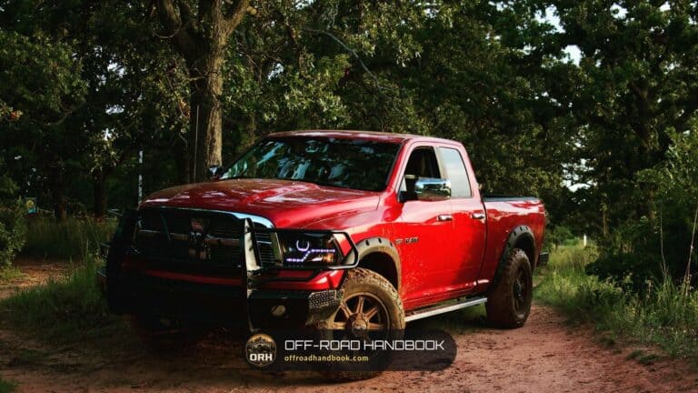 Red pickup truck with a push bar parked on a dirt road in a forest