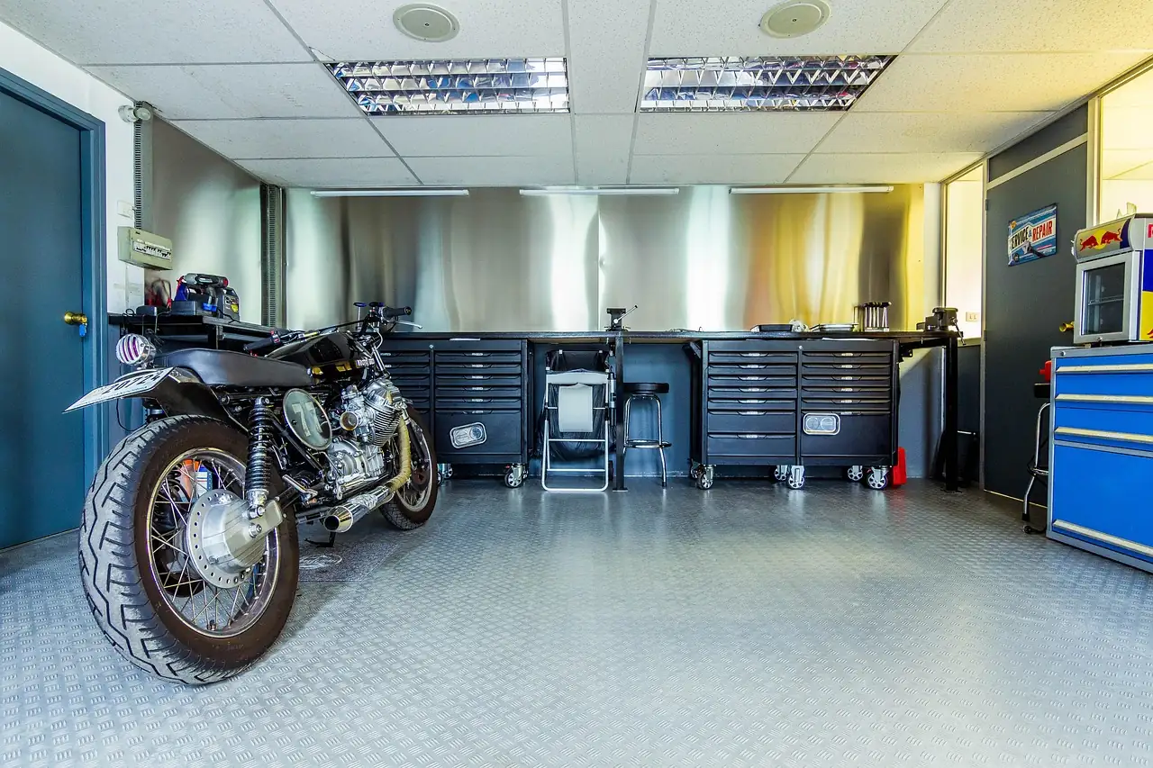 Clean home workshop with a motorcycle parked in front of a rolling tool chest bench
