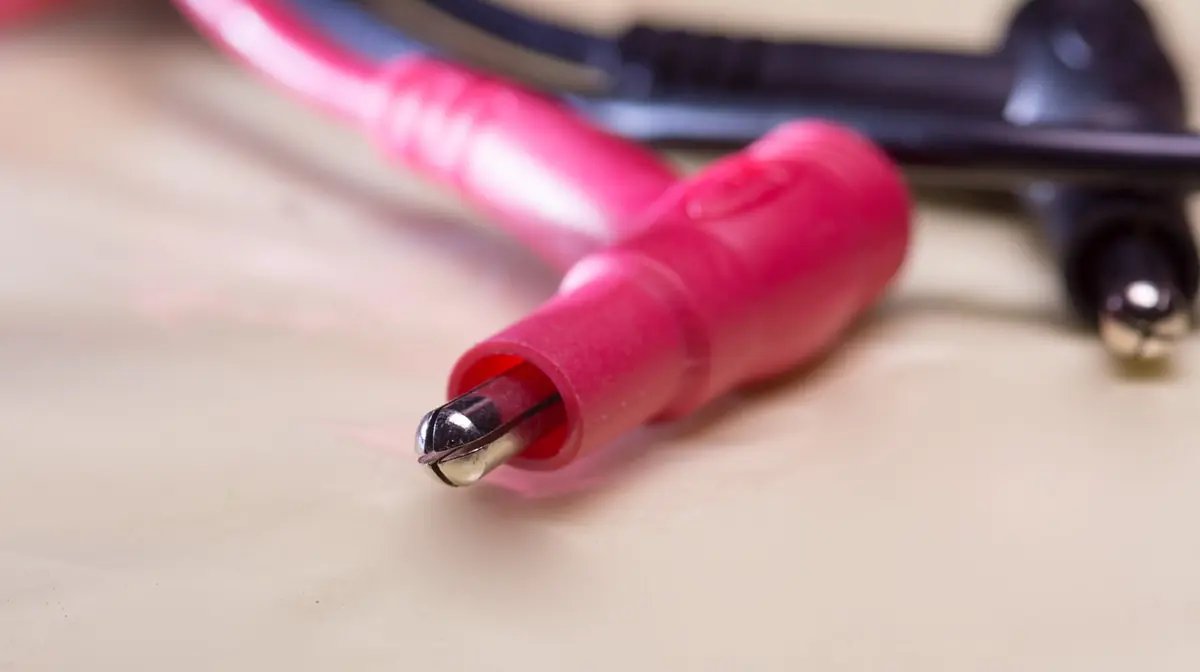 Close-up of a red multimeter test probe used to measure battery and charging voltage (stock photo)
