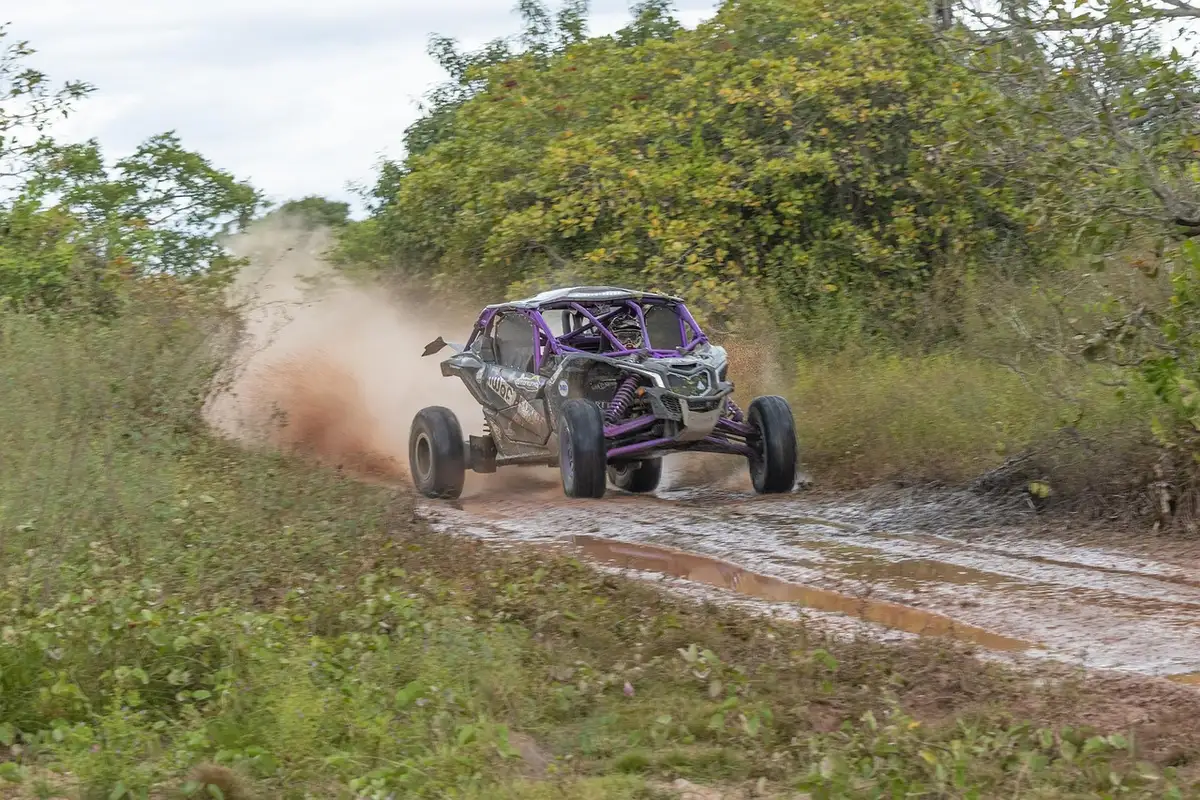 Side-by-side UTV splashing through a muddy puddle on a dirt track