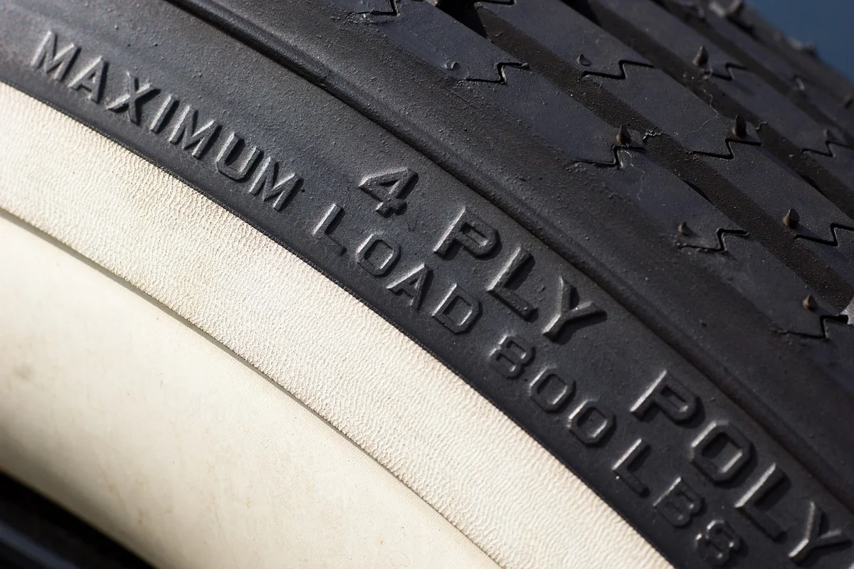 Sidewall of an old whitewall tire with raised text reading 4 ply and maximum load