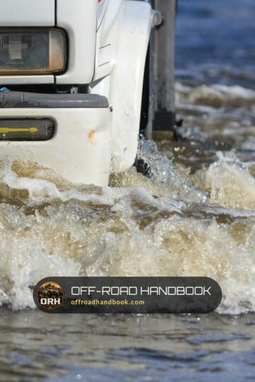 Front of a white SUV pushing a bow wave through deep moving water — Off-Road Handbook