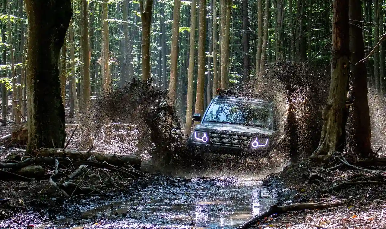 SUV splashing through a muddy forest trail