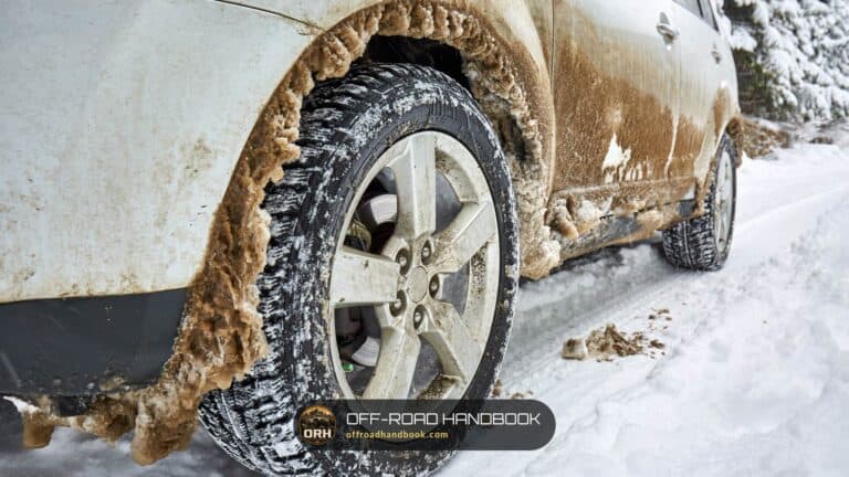 Close-up of an SUV alloy wheel and aggressive tire caked in mud and snow — Off-Road Handbook