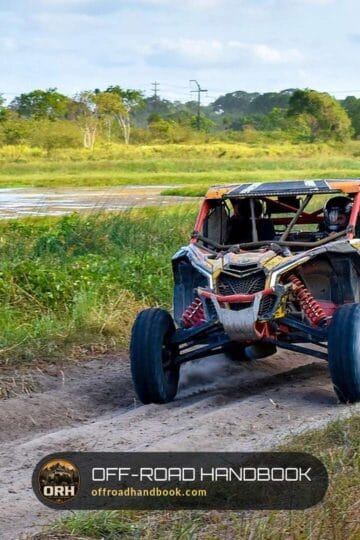 Side-by-side UTV kicking up dust on a dirt trail beside a river — Off-Road Handbook