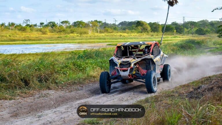 Side-by-side UTV kicking up dust on a dirt trail beside a river — Off-Road Handbook