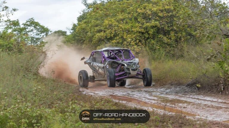 Sport side-by-side UTV kicking up dust on a muddy dirt trail — Off-Road Handbook