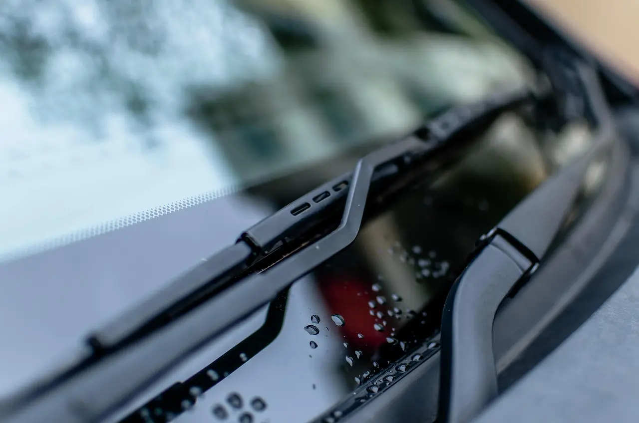 Close-up of a windshield wiper blade and arm resting on clean glass